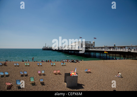 Menschen und Liegestühle am Strand am Pier von Brighton. Stockfoto