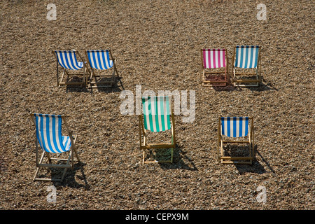 Bunt gestreifte Liegestühle am Strand von Brighton. Stockfoto