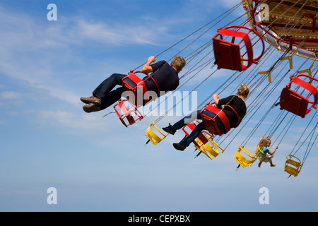 Menschen, die genießen einer Fahrt auf einem traditionellen Chair-o-Plane-Karussell auf einer Messe in Whitstable. Stockfoto