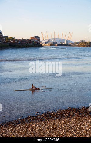 Ein Ruderer training auf der Themse mit O2 im Hintergrund. Stockfoto