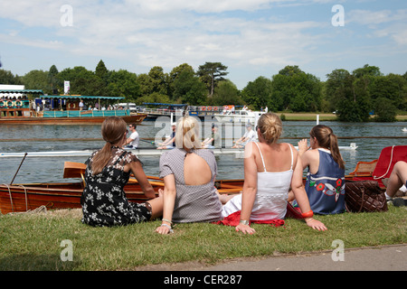 Vier junge Frauen sitzen am Ufer des Flusses genießen die jährliche Henley Royal Regatta. Stockfoto