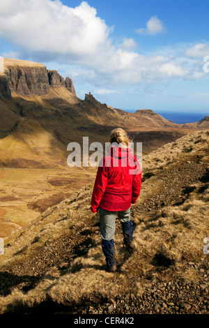 Eine weibliche Walker tragen eine rote wasserdichte Blick auf die atemberaubende Landschaft auf der Halbinsel Trotternish aus der Quiraing. Stockfoto