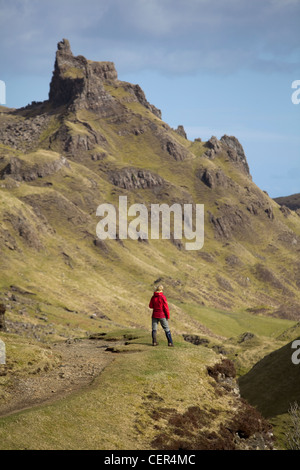 Eine weibliche Walker tragen eine rote wasserdicht steht, um die Aussicht aus einem Pfad über die Quiraing bewundern. Stockfoto