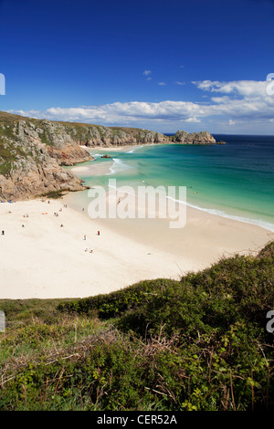 Menschen, die die Sonne am Strand von Porthcurno mit Logan Rock in der Ferne zu genießen. Der Strand und die Bucht gelten als eine der t Stockfoto