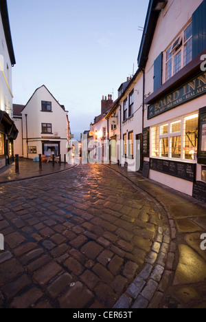 Traditionelle gepflasterten Straße Wicklung gegenüber dem Vorstand Inn Pub in Whitby. Stockfoto