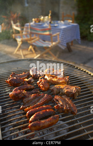 Fleisch grillen auf Holzkohle Grill in einem Dorset Garten auf einem Sommer-Abend, England, UK Stockfoto