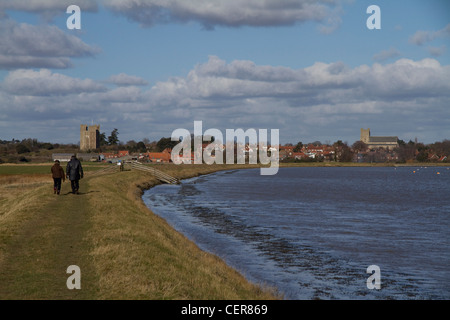 Blick entlang der Ufermauer in Richtung Fischen Dorf von Orford mit der Burg im Hintergrund, Suffolk, England Stockfoto