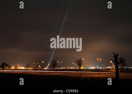 Lichtspur aus einem Flugzeug abheben vom Flughafen London Heathrow in der Abenddämmerung. Stockfoto