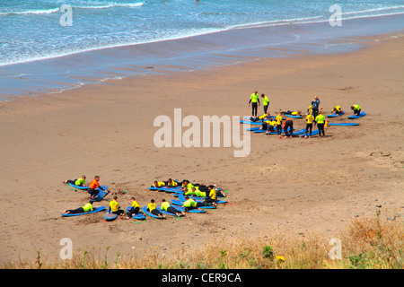 Zwei Gruppen von Urlauber am Sandstrand am Widemouth Bucht an der Nordküste von Cornwall in der Nähe von Bude Surfen lernen. Stockfoto