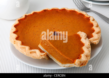 GESAMTE KÜRBISKUCHEN MIT GESCHNITTENEN SCHEIBE Stockfoto