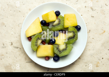 Neue Jahre Resolutionen gesunde Entscheidungen Weißware Teller auf einem natürlichen farbigen Hintergrund auf dem Teller ist ein Obstsalat gemacht von Stockfoto