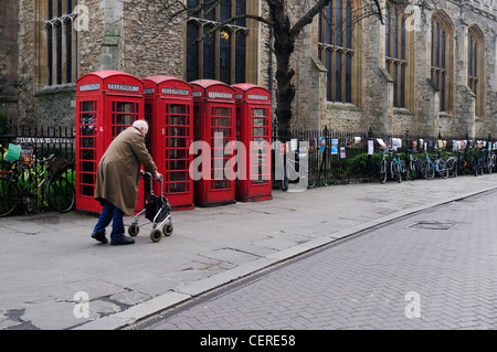 Ein senior Mann zu Fuß vorbei an rote Telefonzellen außerhalb Great St. Mary's-Kirche in St. Mary Street. Stockfoto