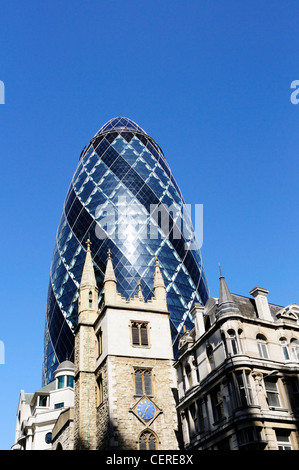 30 St Mary Axe, die Swiss Re Gebäude bekannt als The Gherkin, überragt von St. Andrew Undershaft in der City of London. Stockfoto