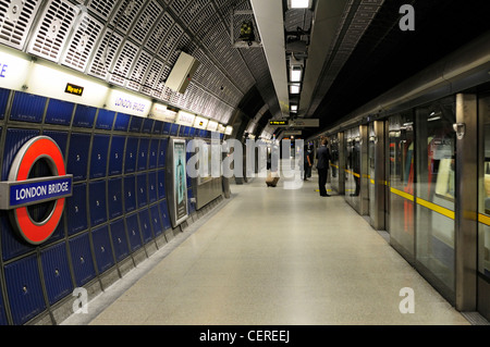 Passagiere, die darauf warten, einen Schlauch an Bord trainieren auf einer Plattform der Jubilee Line in London Brücke u-Bahnstation. Stockfoto