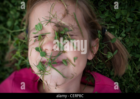 In der Nähe des sechs Jahre alten Mädchen vertuscht Kleeblätter und Rasen, Verlegung auf Boden, Sommer. Stockfoto