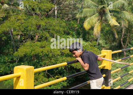 Kleinen einheimischen jungen genießen die Fluss Wasser Landschaft von der Spitze der Eisenbahn Bridge.Beautiful Kerala Landschaften auf Hintergrund Stockfoto