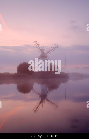 Eine neblige Sicht über das Wasser zu Thurne Mill bei Sonnenaufgang. Stockfoto