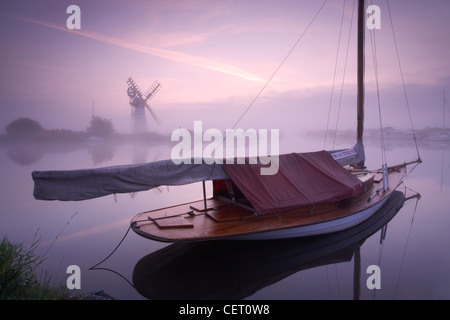 Eine neblige Sicht über das Wasser zu Thurne Mill bei Sonnenaufgang. Stockfoto