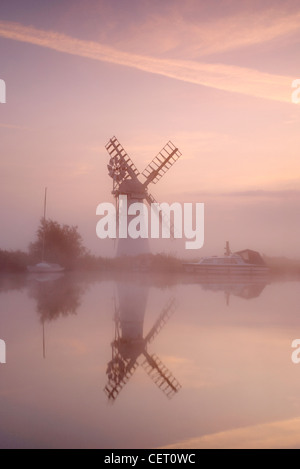 Eine neblige Sicht über das Wasser zu Thurne Mill bei Sonnenaufgang. Stockfoto