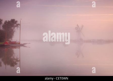 Eine neblige Sicht über das Wasser zu Thurne Mill bei Sonnenaufgang. Stockfoto