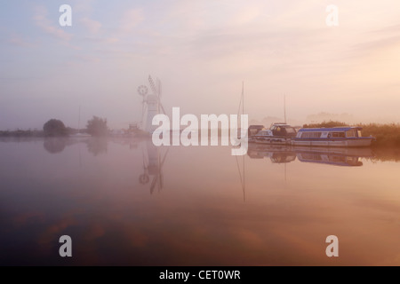 Eine neblige Sicht über das Wasser zu Thurne Mill bei Sonnenaufgang. Stockfoto