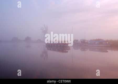 Eine neblige Sicht über das Wasser zu Thurne Mill bei Sonnenaufgang. Stockfoto