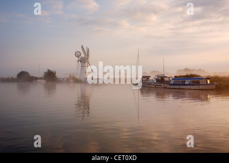 Eine neblige Sicht über das Wasser zu Thurne Mill bei Sonnenaufgang. Stockfoto