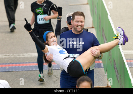 Anglo Mann trägt Frau über die Ziellinie beim Austin-Marathon in der Innenstadt von Austin Texas. Stockfoto