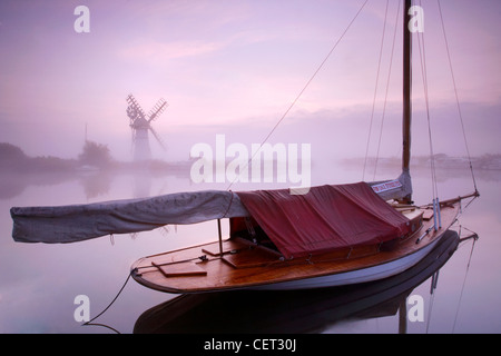 Boote von Thurne Mill bei Sonnenaufgang auf den Norfolk Broads in Nebel gehüllt. Stockfoto