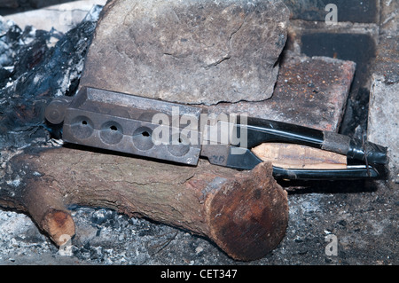 Schmelzendes Blei, um selbstgemachte Sinker zum Angeln herzustellen. Geschmolzenes Metall wird aus einer Pfanne in eine quadratische Gussform in einer Metallwerkstatt gegossen. Stockfoto