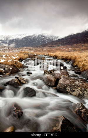 Wasser fließt nach unten von Bergen über Felsen in Snowdonia-Nationalpark im Winter. Stockfoto