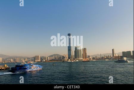 Morgen Blick auf Victoria Harbour mit dem ICC Tower im Hintergrund und einem TurboJet Boot verlassen das Macau Ferry terminal. Stockfoto