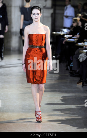 Loewe Paris bereit zu tragen Herbst Winter Knie Länge metallic Orange trägerlosen Kleid mit brauner Gürtel und rote Sandalen Stockfoto