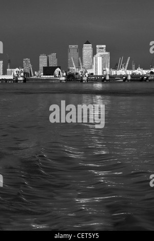 Canary Wharf, The Millenium Dome und der Thames Barrier in schwarz / weiß genommen von einem Boot auf der Themse Stockfoto