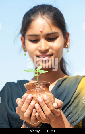 Indische Teenager-Mädchen hält einen Pflanze Setzling in einem Tontopf. Indien Stockfoto
