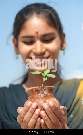 Indische Teenager-Mädchen hält einen Pflanze Setzling in einem Tontopf. Indien Stockfoto