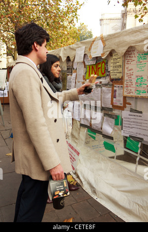 Ein paar schauen Antikapitalismus Poster von London besetzen Demonstranten auf ihre Zelte in der Nähe von St. Pauls Cathedral in London angezeigt Stockfoto