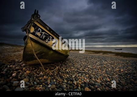 Eine alte gelbe Ruderboot auf einem Kiesstrand in Fleetwood. Stockfoto