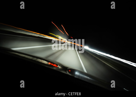 Blick aus einem fahrenden Auto auf Lichtspuren auf der Autobahn M1 in der Nacht. Stockfoto