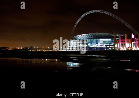 Ein Blick über das Wasser zu einem beleuchteten Wembley-Stadion in der Nacht. Stockfoto