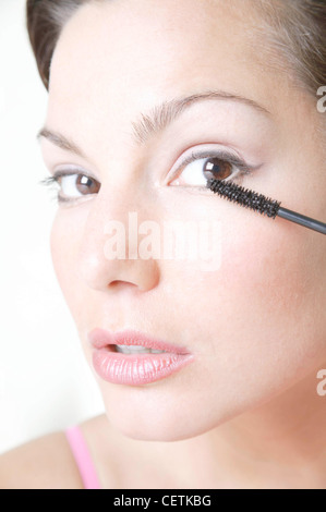 Semi-Profil des weiblichen brünette Haare vom Gesicht blass rosa Lidschatten und flüssigen Eyeliner rosa Lippenstift auftragen von Wimperntusche tragen Stockfoto