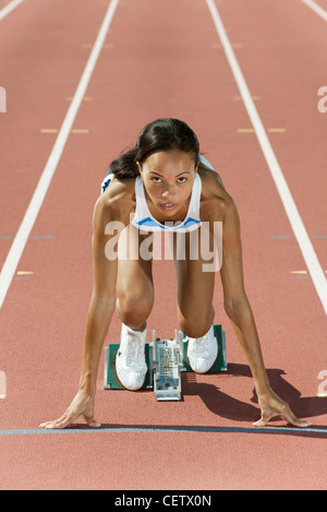 Frau kauerte in Startposition auf Laufband Stockfoto