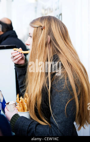 Portobello Road Street Market London hübsche junge brunette Mädchen lange Haar essen Churro churros Spanisch donut Donut Stockfoto