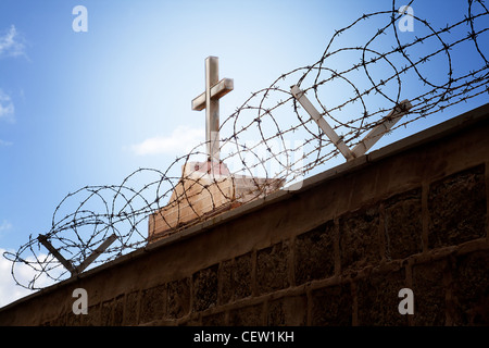 Krieg und Religion Konzept - Kreuz und Stacheldraht über blauen Himmel Stockfoto