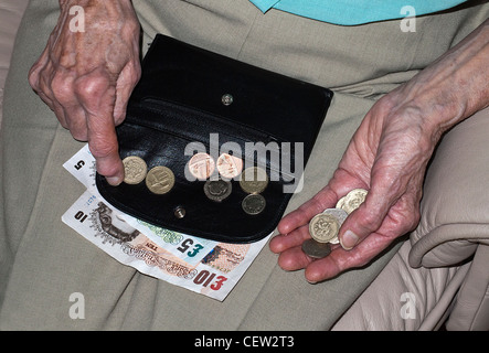 Hände von einer älteren Dame zählen Geld in Sterling Banknoten und Münzen Stockfoto