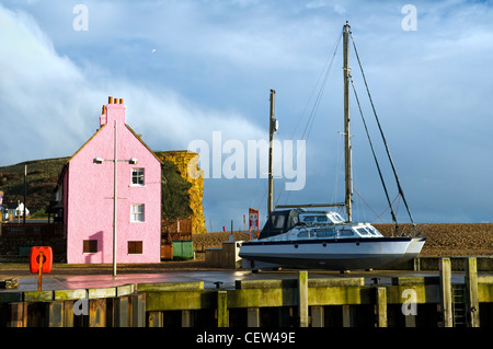 Bunte Szene Haus, Felsen und Boot im Hafen von West Bay in der Nähe von Bridport, Dorset, England nach einem Sturm im Winter genommen Stockfoto