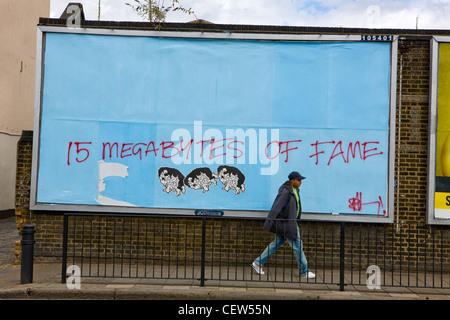 Mann zu Fuß vorbei an "15 Megabyte Ruhm Graffiti", Hackney, London Stockfoto