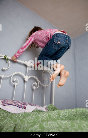 Sieben Jahre altes Mädchen hält Bettrahmen und von ihrem Bett hoch zu springen. Stockfoto