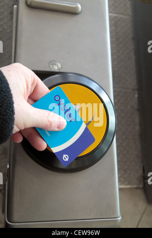 Ein Mann streichen seine Brieftasche (enthält eine Oystercard) auf eine berühren und Pay Leser an Pudding Mill Lane DLR Station, London, UK. Stockfoto