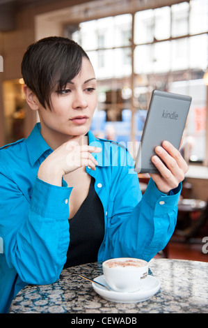 Junge Frau lesen ebook auf eine Amazon Kindle, Großbritannien Stockfoto